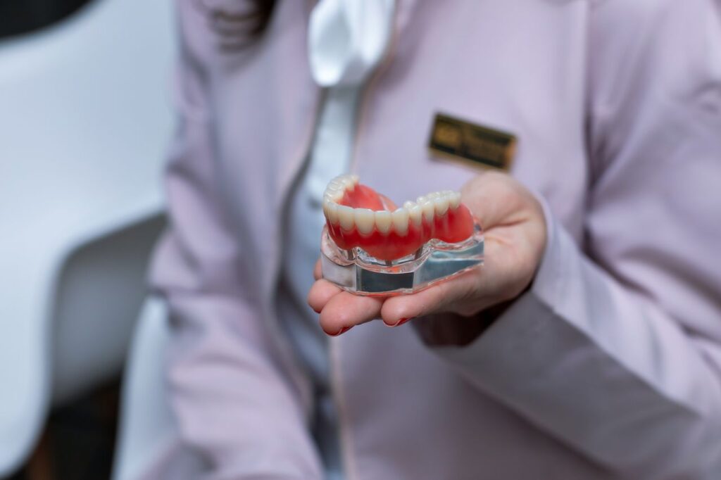 Dentista mostrando un modelo dental para explicar los distintos tipos de implantes